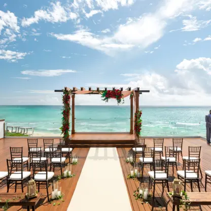 Oceanfront terrace wedding ceremony with floral pergola at Hilton Playa Del Carmen