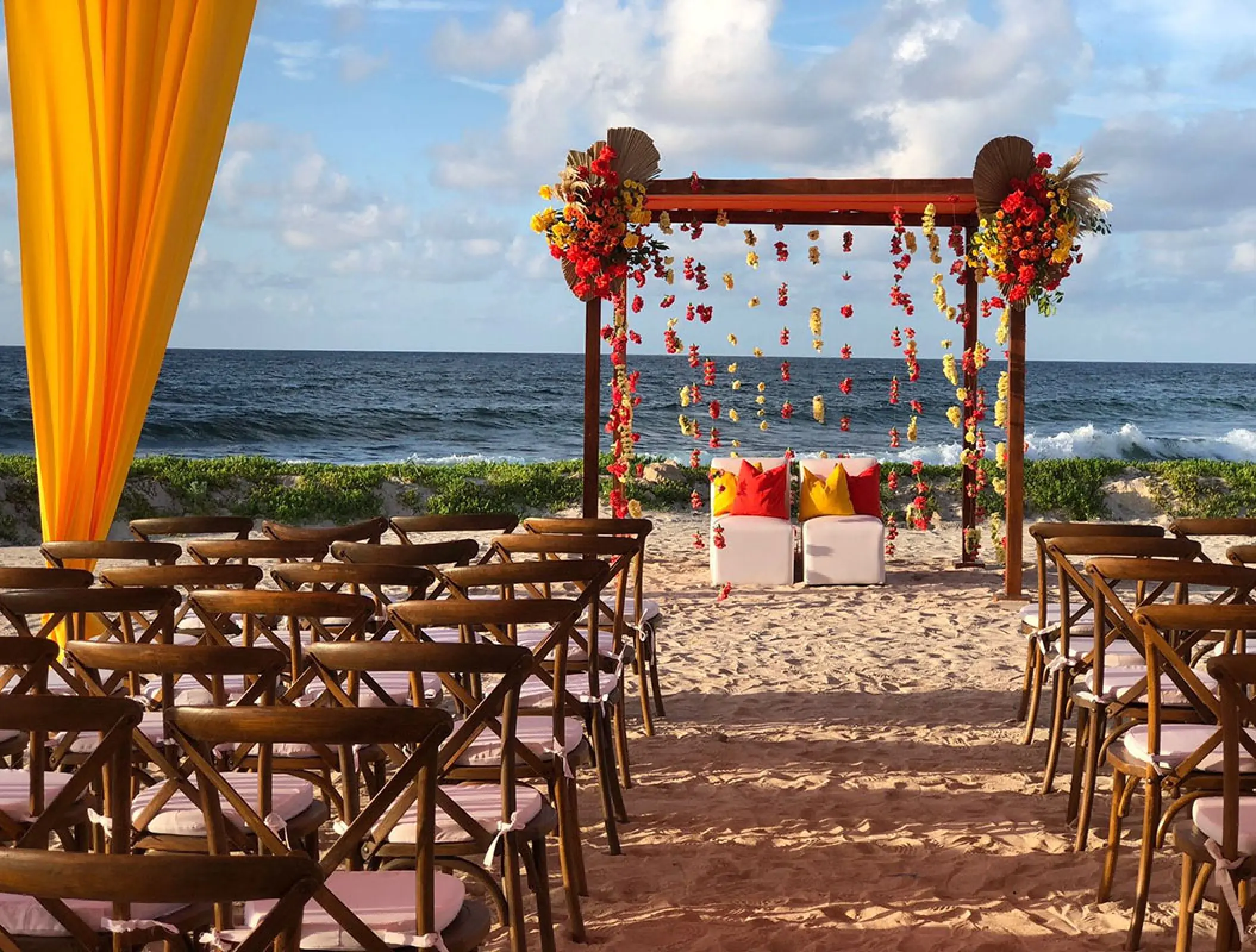 Beachfront wedding ceremony with wooden arbor and floral decor at Hilton Tulum, Tulum