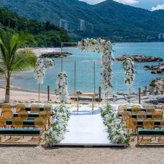 Beachfront wedding ceremony with white flowers and gold chairs at Hilton Vallarta Riviera, Puerto Vallarta