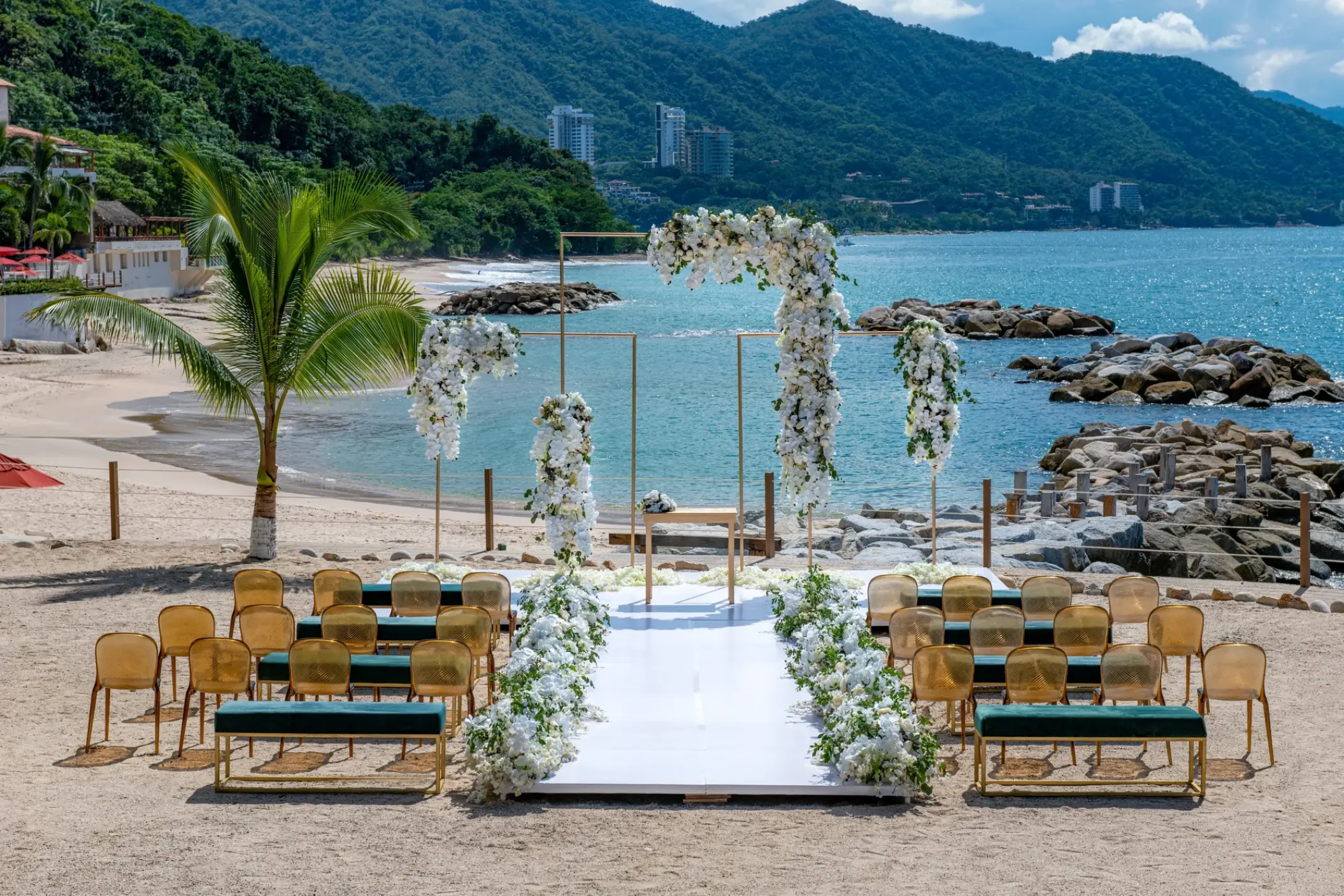 Beachfront wedding ceremony with white flowers and gold chairs at Hilton Vallarta Riviera, Puerto Vallarta