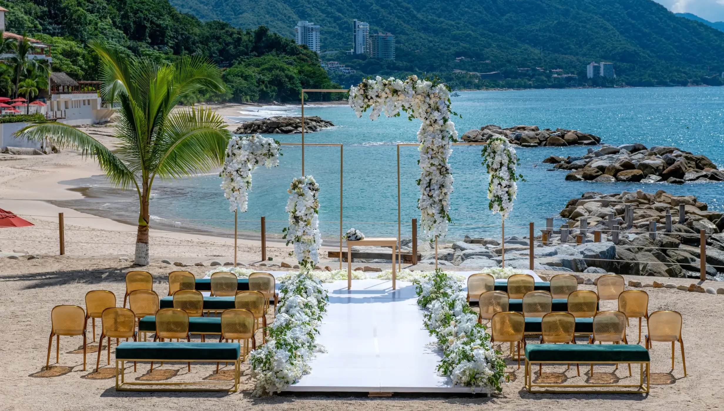 Beachfront wedding ceremony with white flowers and gold chairs at Hilton Vallarta Riviera, Puerto Vallarta