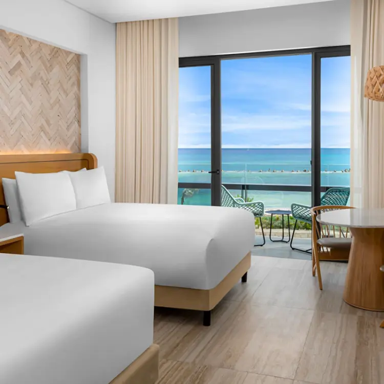 Two queen beds in a guest room with an ocean view balcony at Hilton Tulum