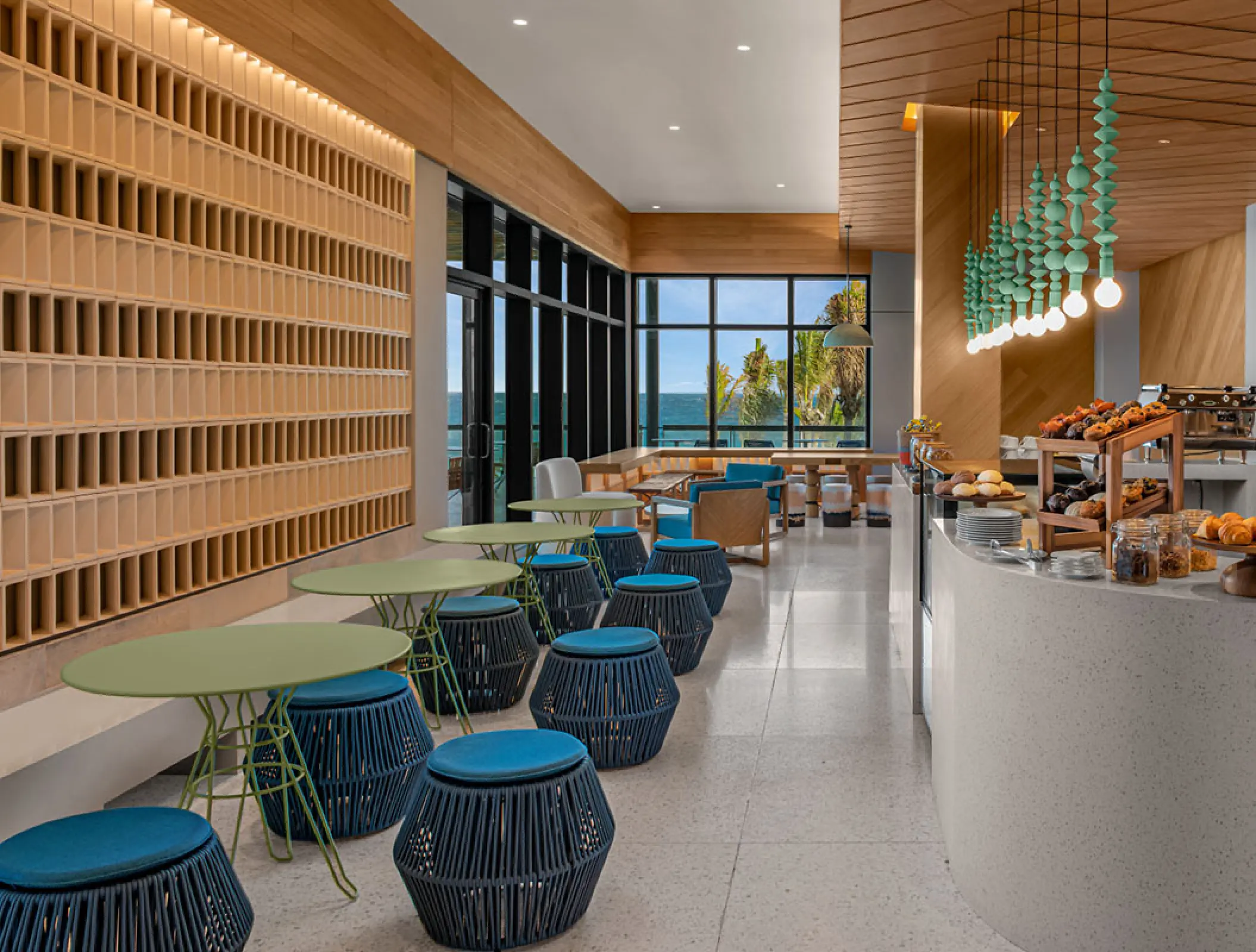 Modern cafe interior with blue woven stools and wood paneling at Hilton Tulum