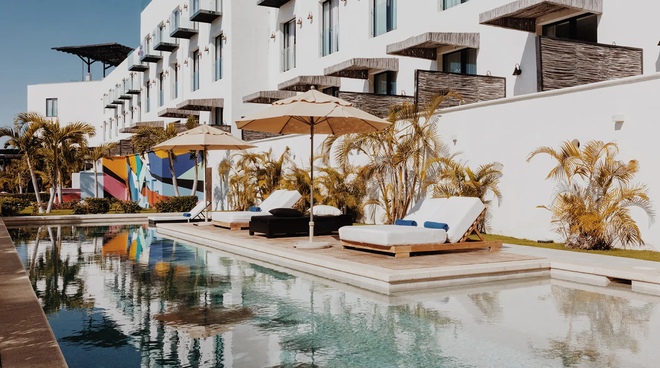 Hotel El Ganzo main pool with lounge chairs and colorful wall mural, Cabo San Lucas