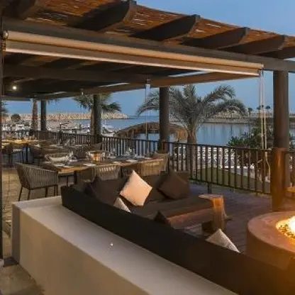 Outdoor terrace with fire pit and dining tables overlooking the marina at Hotel El Ganzo, Cabo San Lucas