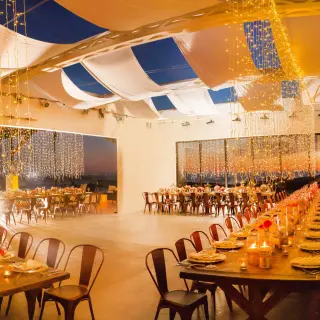 Indoor wedding reception with long wooden tables and string lights at Hotel El Ganzo, Cabo San Lucas