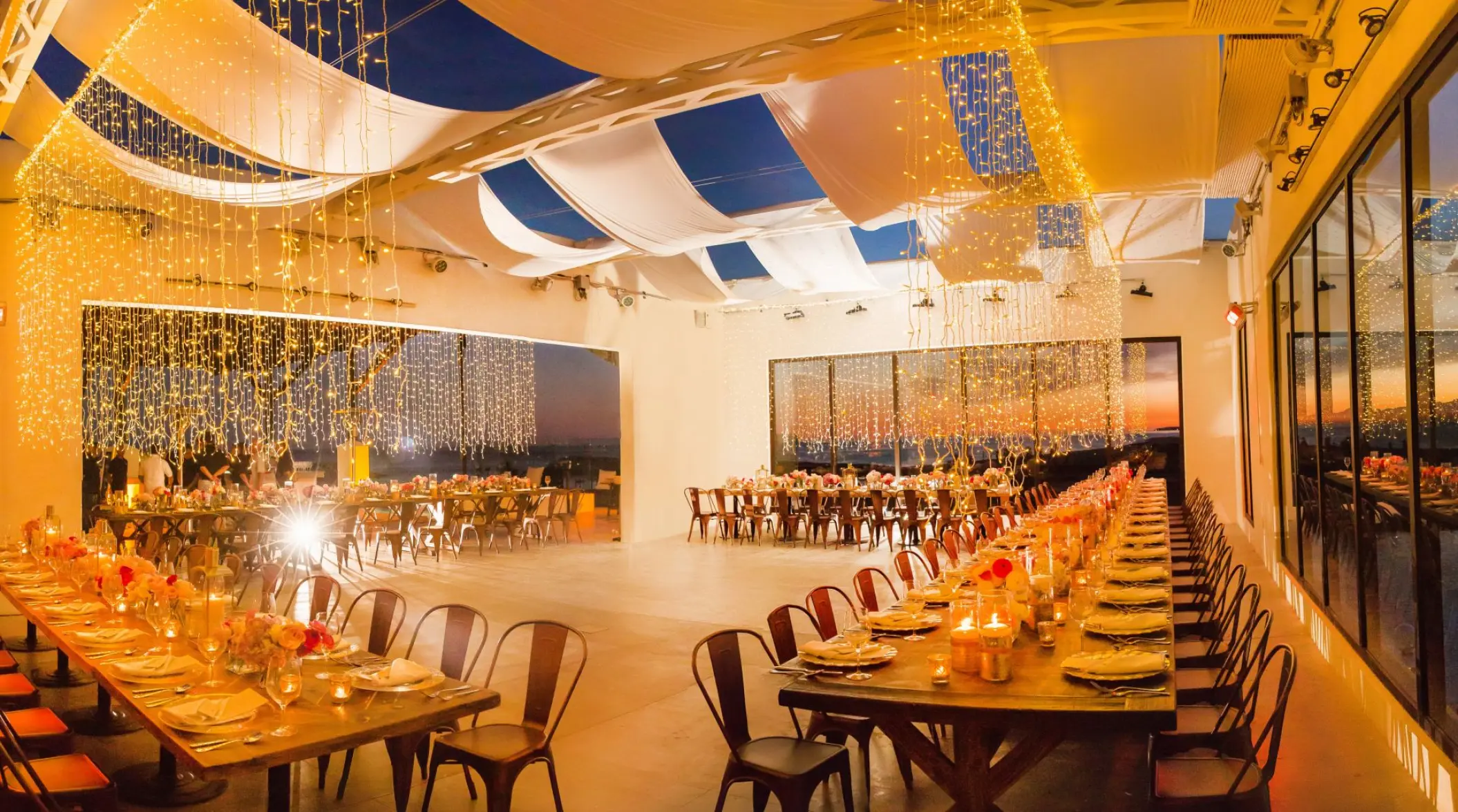 Indoor wedding reception with long wooden tables and string lights at Hotel El Ganzo, Cabo San Lucas