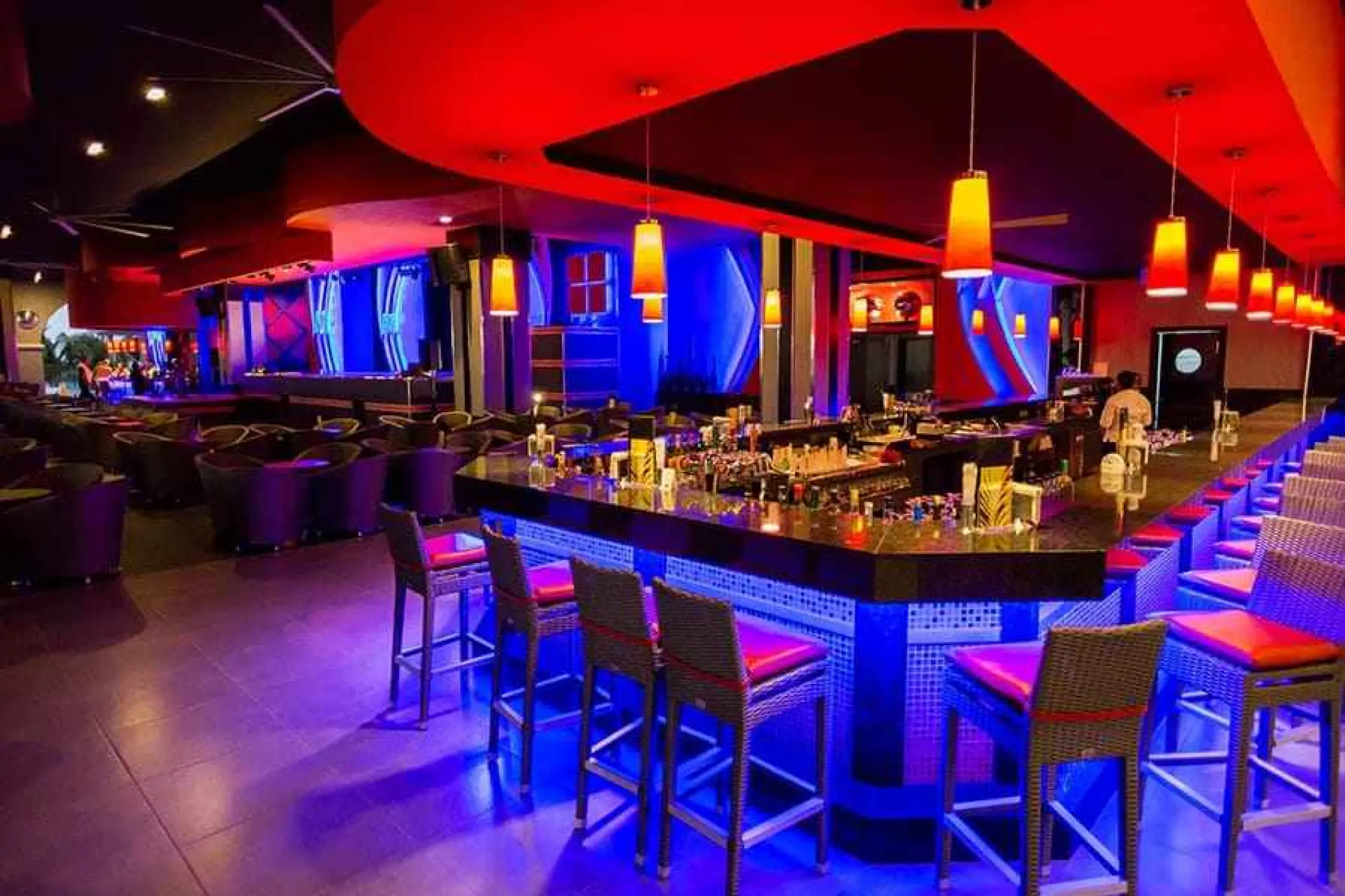 Modern lounge bar with blue neon lighting and orange pendant lamps at Riu Palace Cabo San Lucas