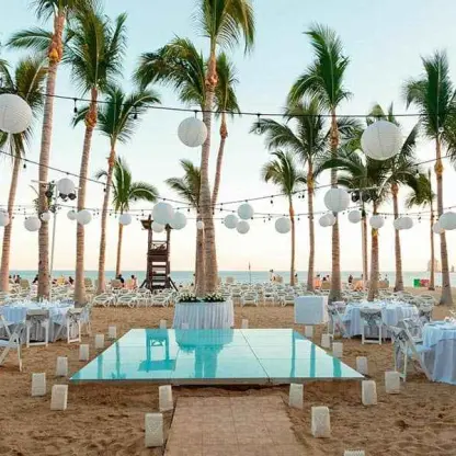 Beach reception setup with a dance floor and paper lanterns at Riu Palace Cabo San Lucas