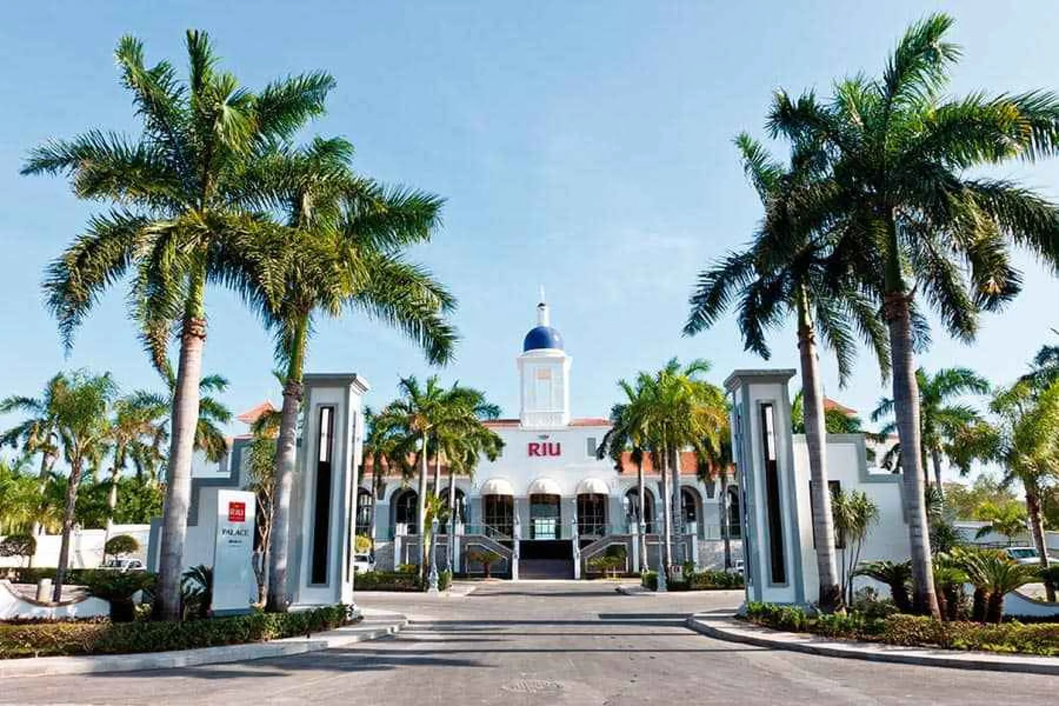 Riu Palace Mexico white facade and entrance framed by palm trees, Playa Del Carmen
