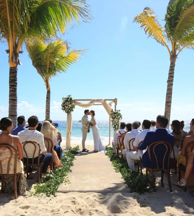 Beachfront wedding ceremony between palm trees at Hotel Xcaret Arte, Riviera Maya