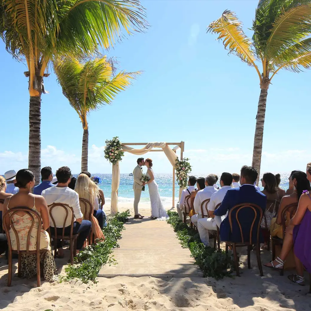 Beachfront wedding ceremony between palm trees at Hotel Xcaret Arte, Riviera Maya