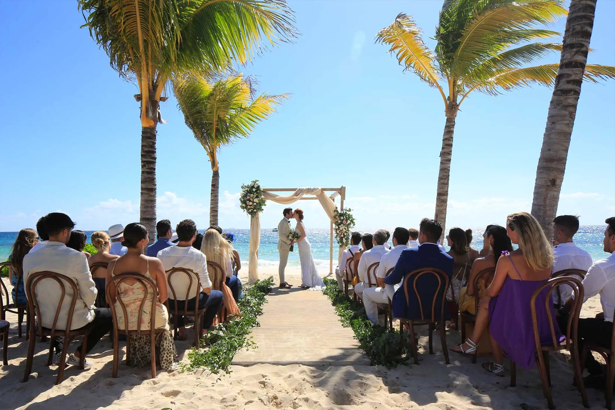 Beachfront wedding ceremony between palm trees at Hotel Xcaret Arte, Riviera Maya