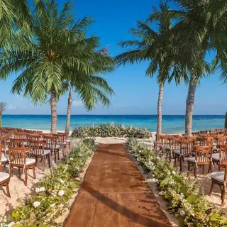 Beachfront wedding ceremony setup with wooden aisle and chairs at Hotel Xcaret Arte, Riviera Maya