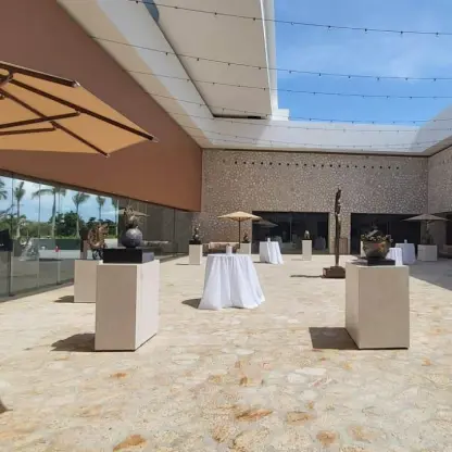Outdoor stone foyer with cocktail tables and modern sculptures at Hotel Xcaret Arte, Riviera Maya