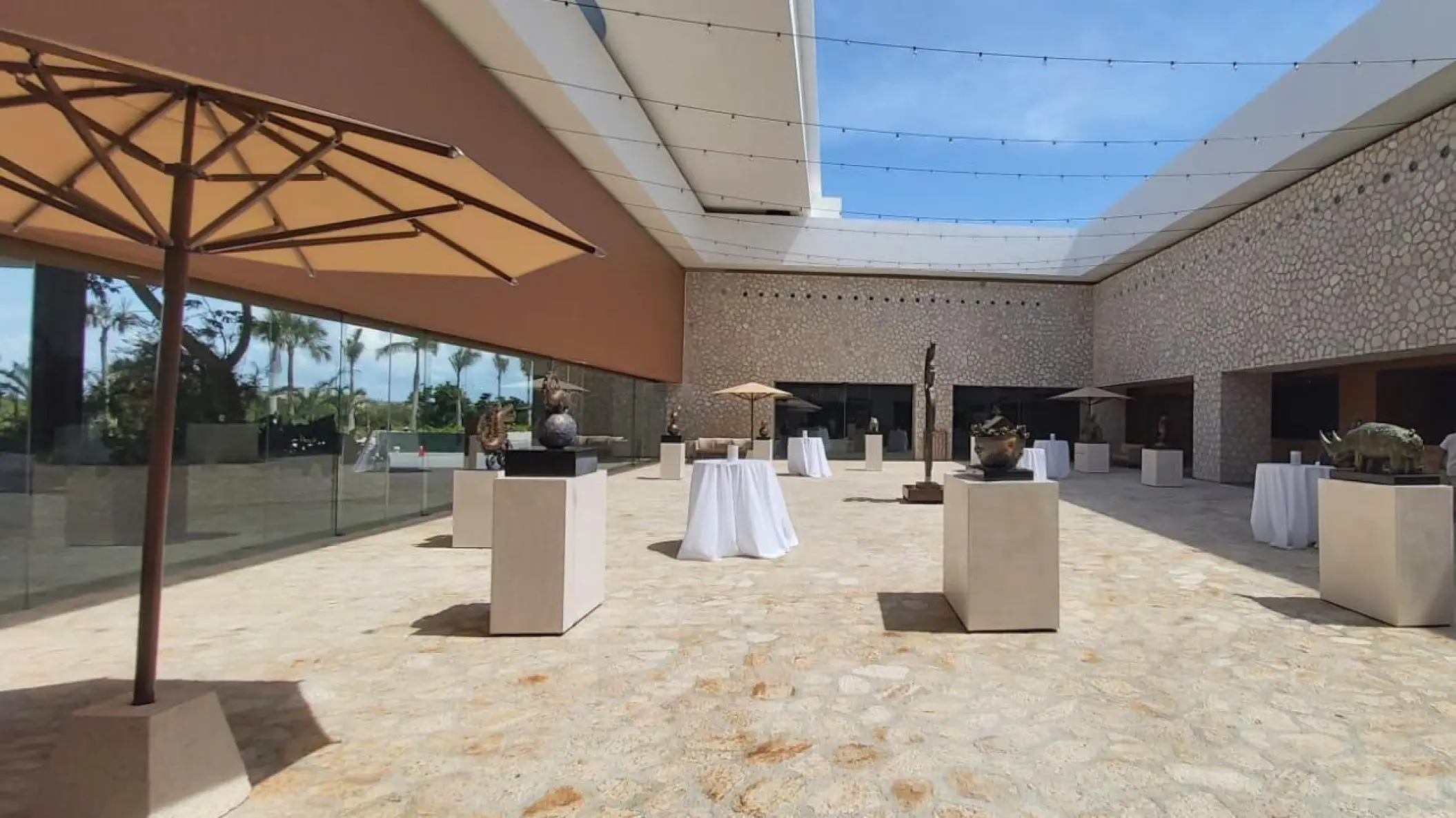 Outdoor stone foyer with cocktail tables and modern sculptures at Hotel Xcaret Arte, Riviera Maya