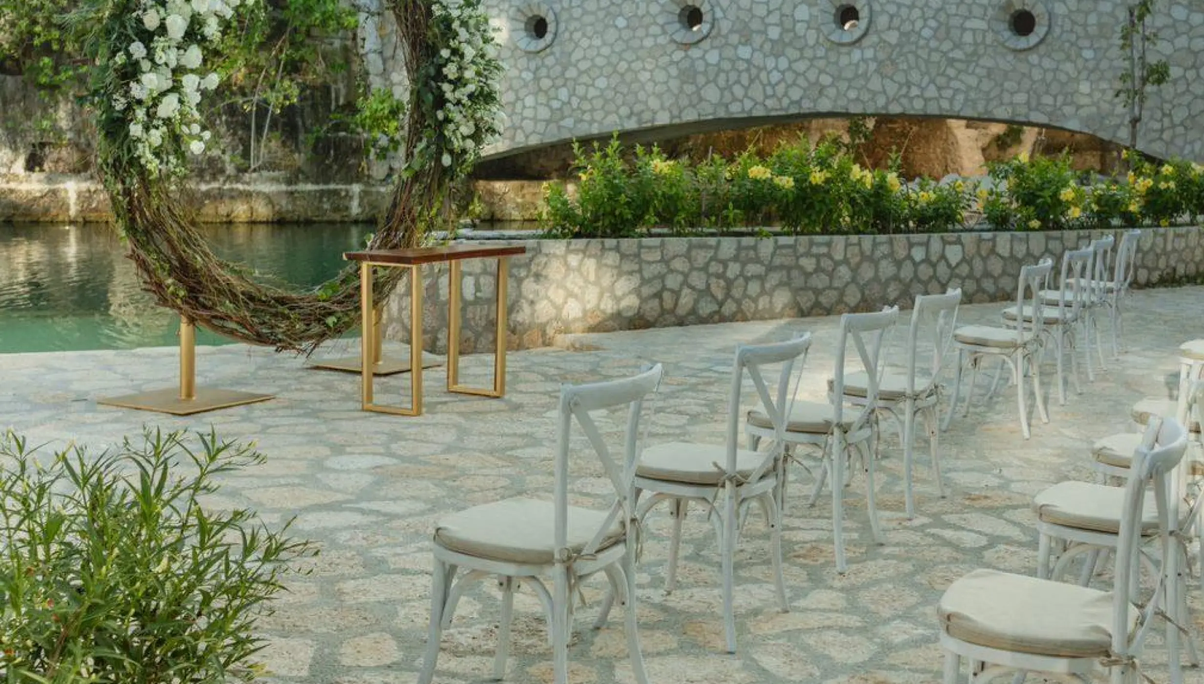 Floral moon gate and white chairs for a wedding ceremony at Hotel Xcaret Arte, Riviera Maya