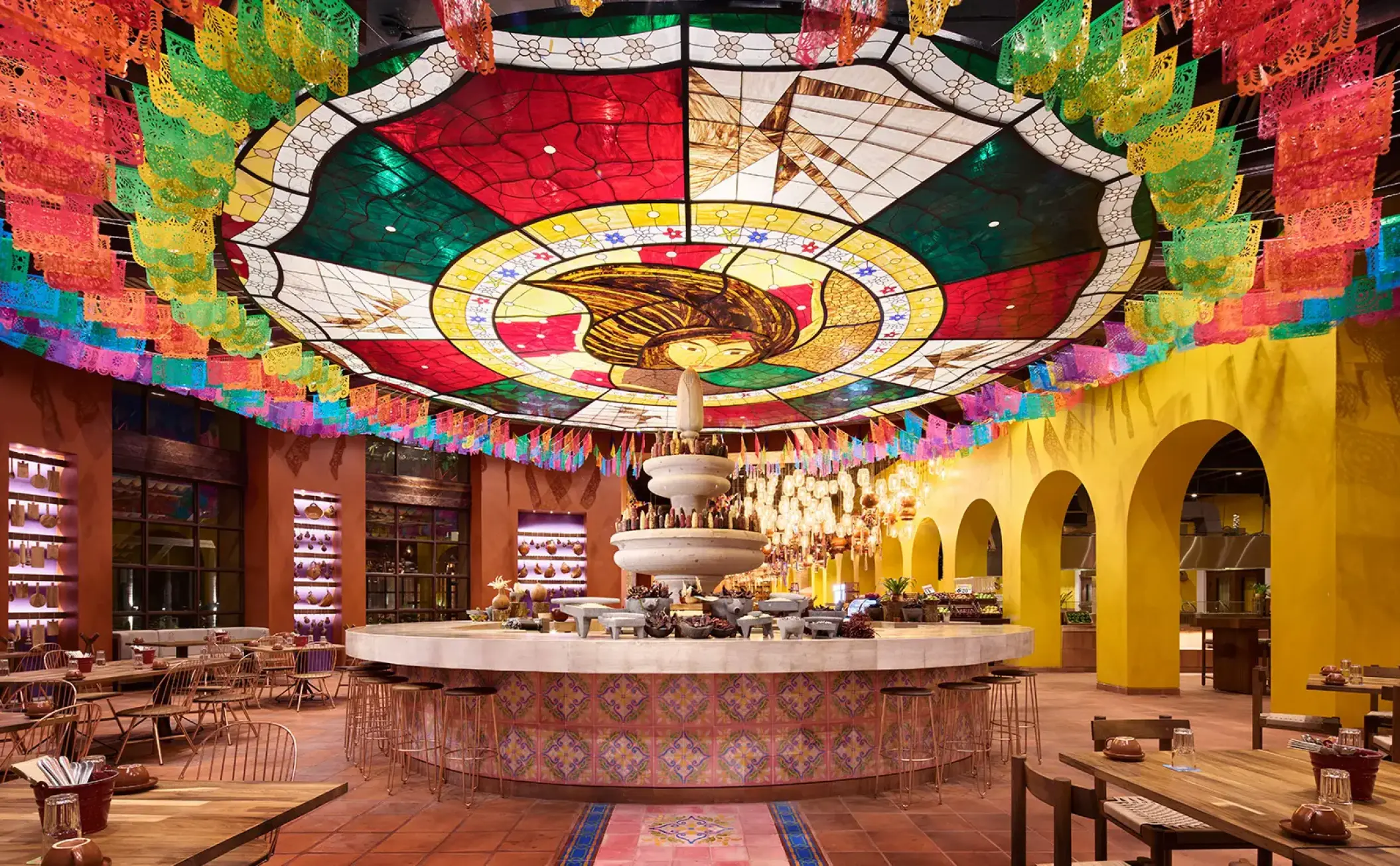 Colorful restaurant with a stained-glass ceiling and papel picado at Hotel Xcaret Arte, Riviera Maya