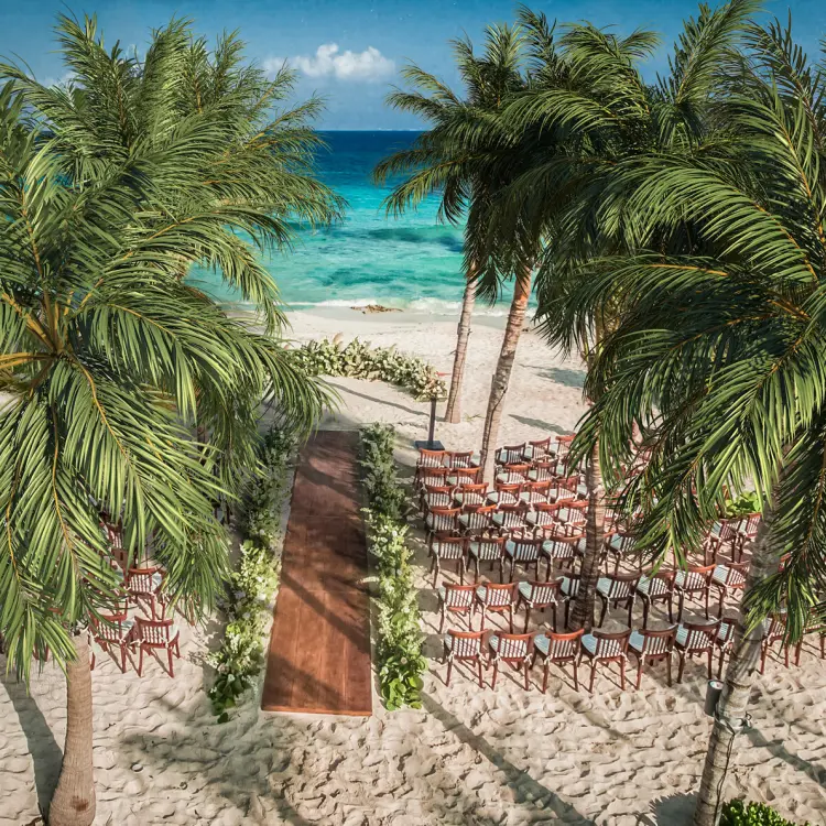 Beachfront wedding ceremony setup with palm trees at Hotel Xcaret Mexico, Riviera Maya