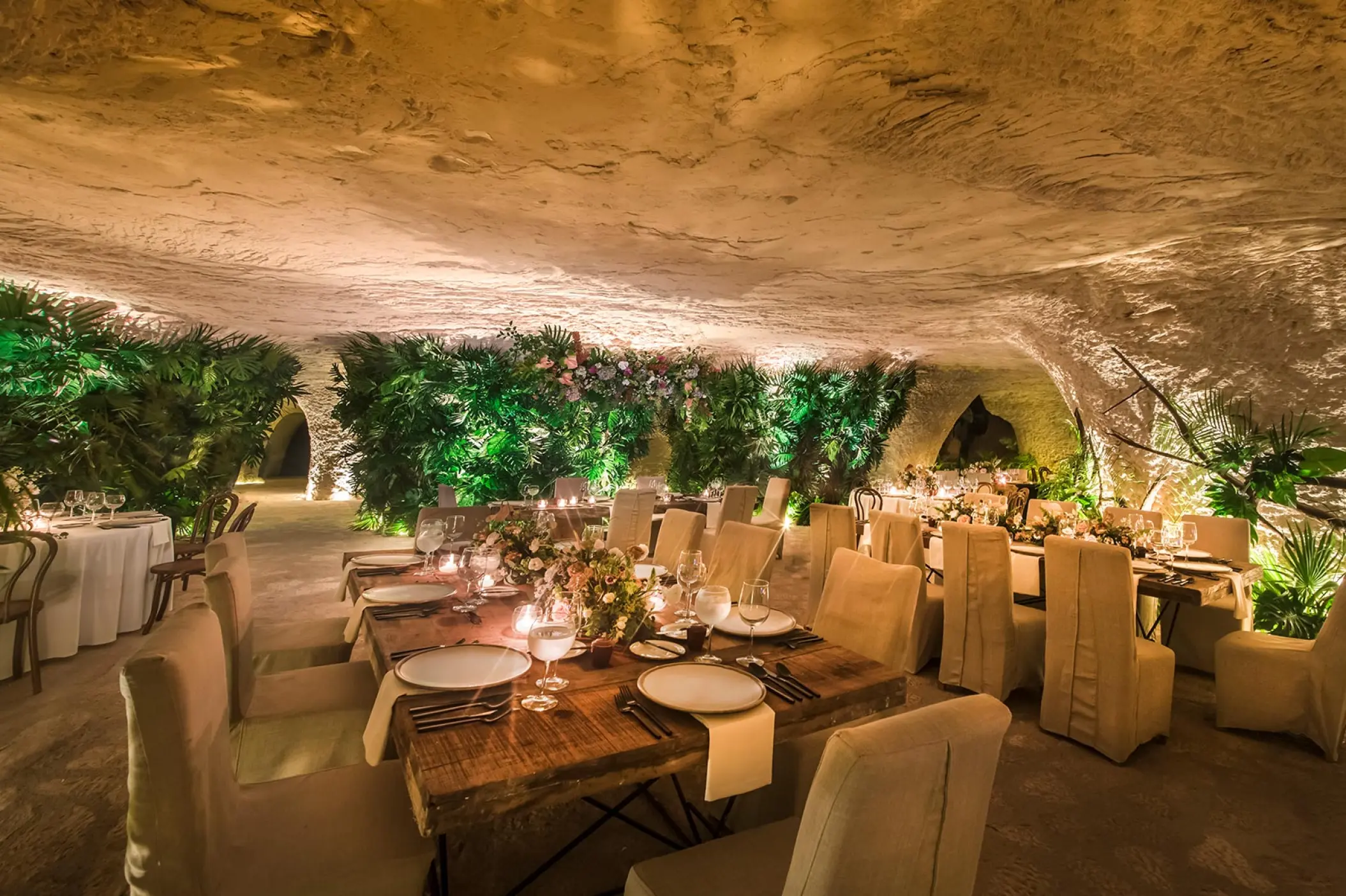 Cave wedding reception with set tables and green foliage at Hotel Xcaret Mexico, Riviera Maya
