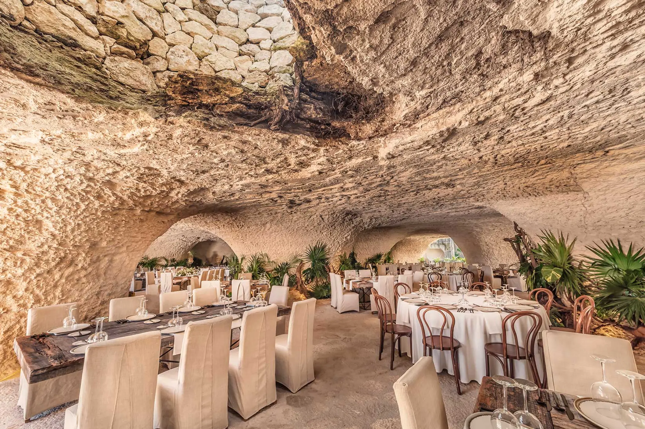 Cave wedding reception venue with set tables and tropical plants at Hotel Xcaret Mexico, Riviera Maya