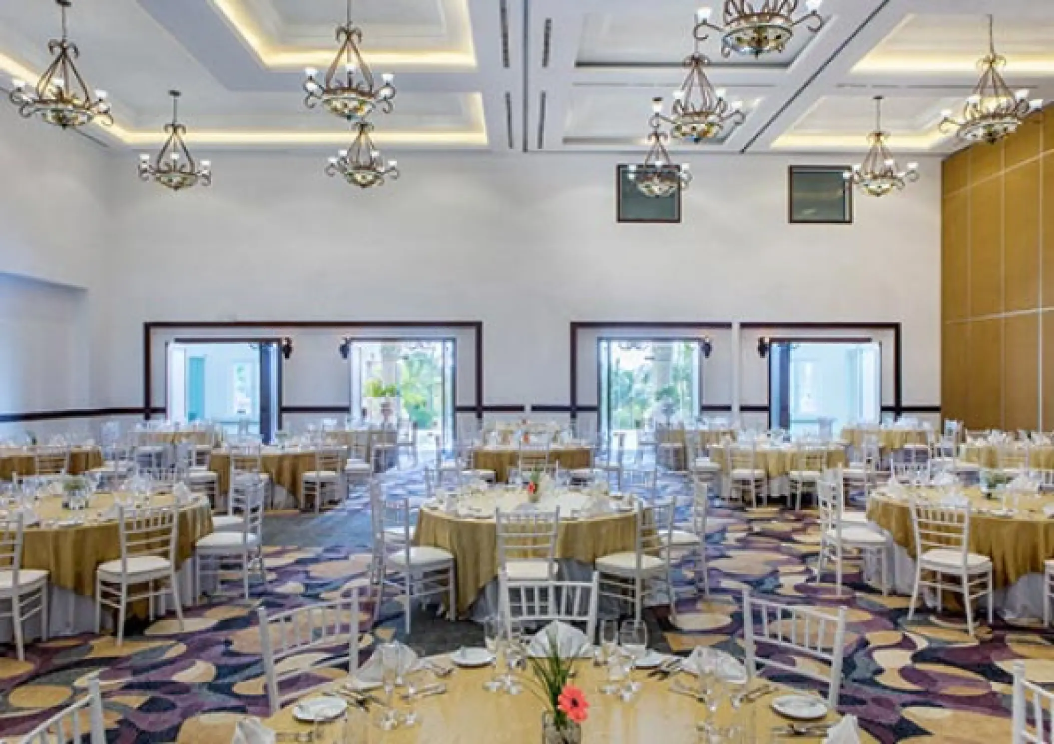 Indoor ballroom wedding reception at Hyatt Zilara Cancun with gold linens and white chairs