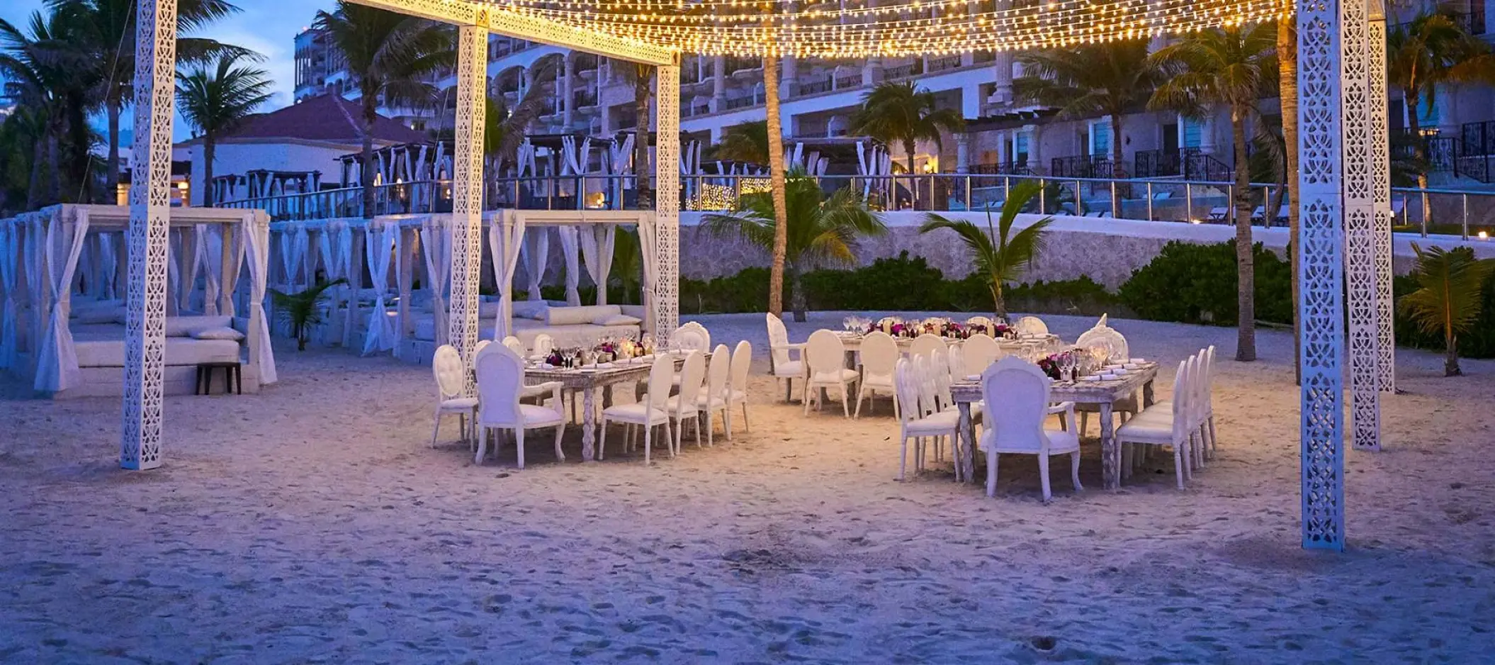 Beach wedding reception with string lights and white tables at Hyatt Zilara Cancun