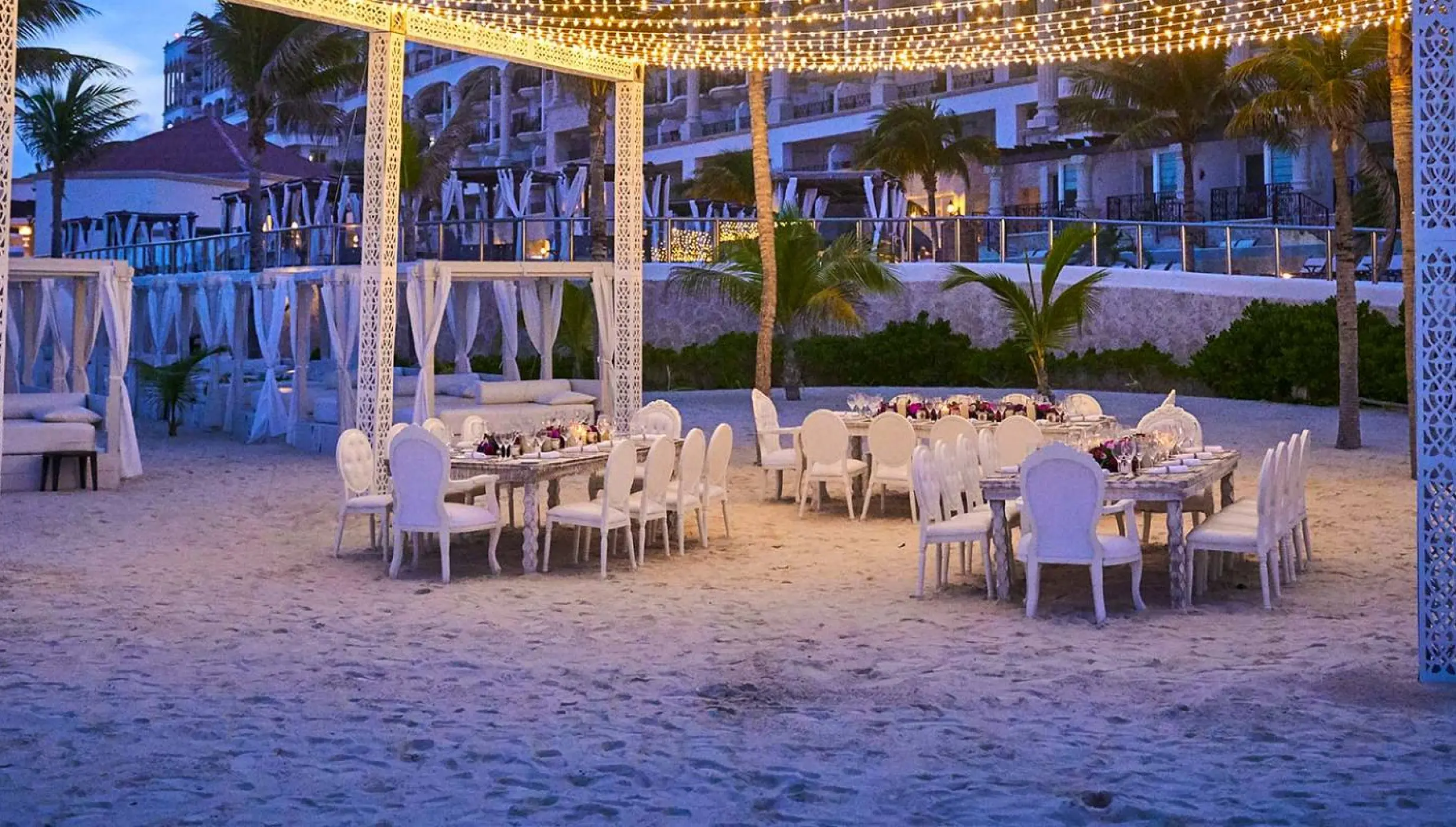Beach wedding reception with string lights and white tables at Hyatt Zilara Cancun