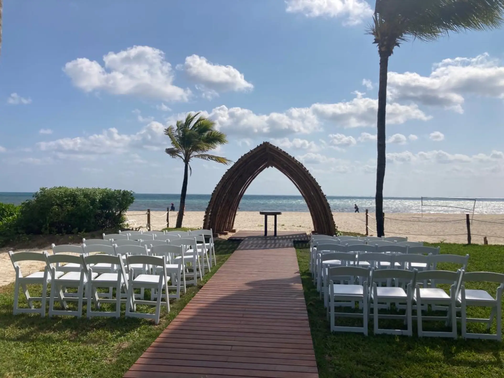 Beachfront wedding ceremony setup with a wooden arch and white chairs at Hyatt Zilara Riviera Maya
