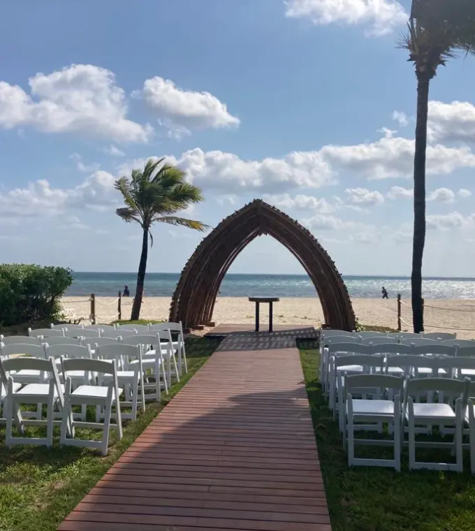 Beachfront wedding ceremony setup with a wooden arch and white chairs at Hyatt Zilara Riviera Maya