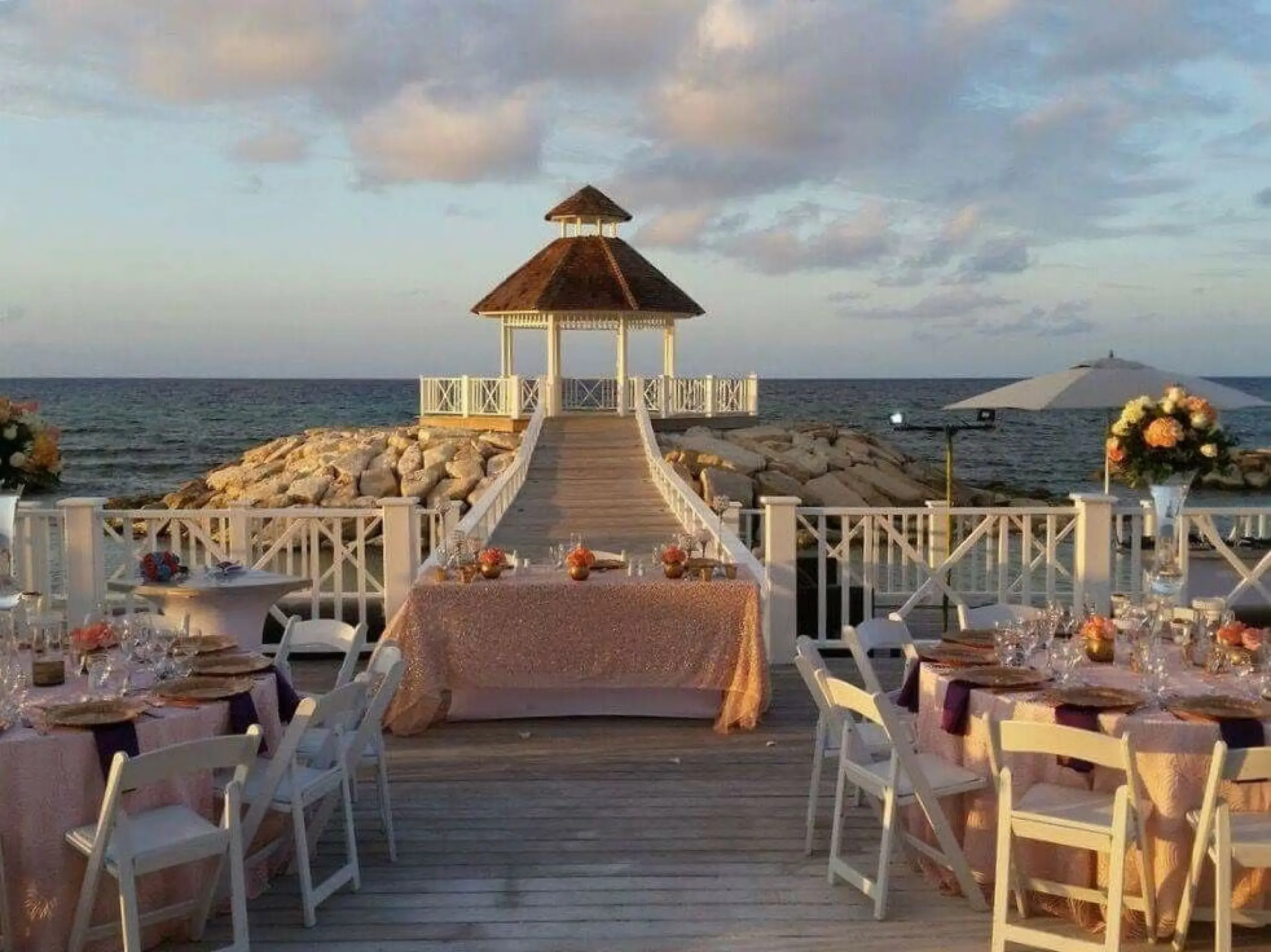 Outdoor wedding reception setup on a pier with an oceanfront gazebo at Hyatt Zilara Rose Hall, Montego Bay