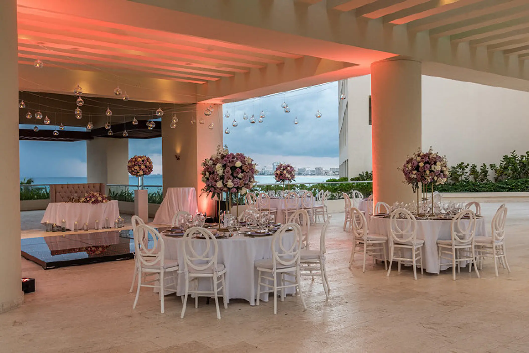 Covered terrace wedding reception with floral centerpieces and white chairs at Hyatt Ziva Cancun, Cancun