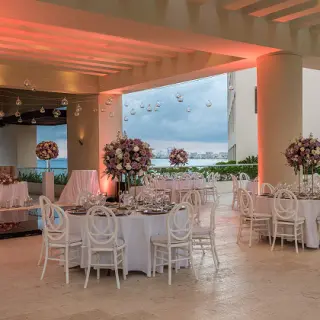 Covered terrace wedding reception with floral centerpieces and white chairs at Hyatt Ziva Cancun, Cancun