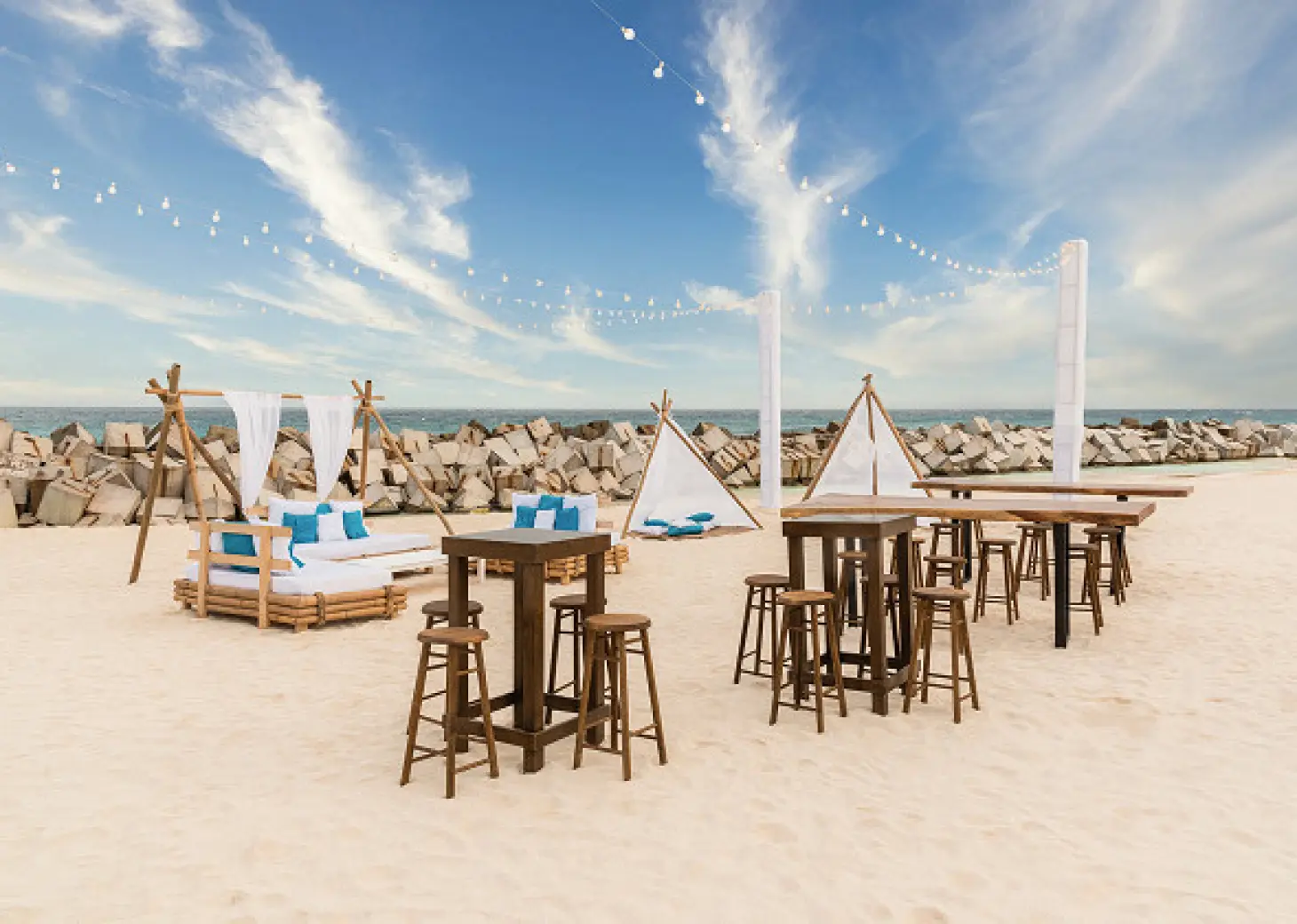 Beachfront wedding reception setup with wooden high-top tables and string lights at Hyatt Ziva Cancun