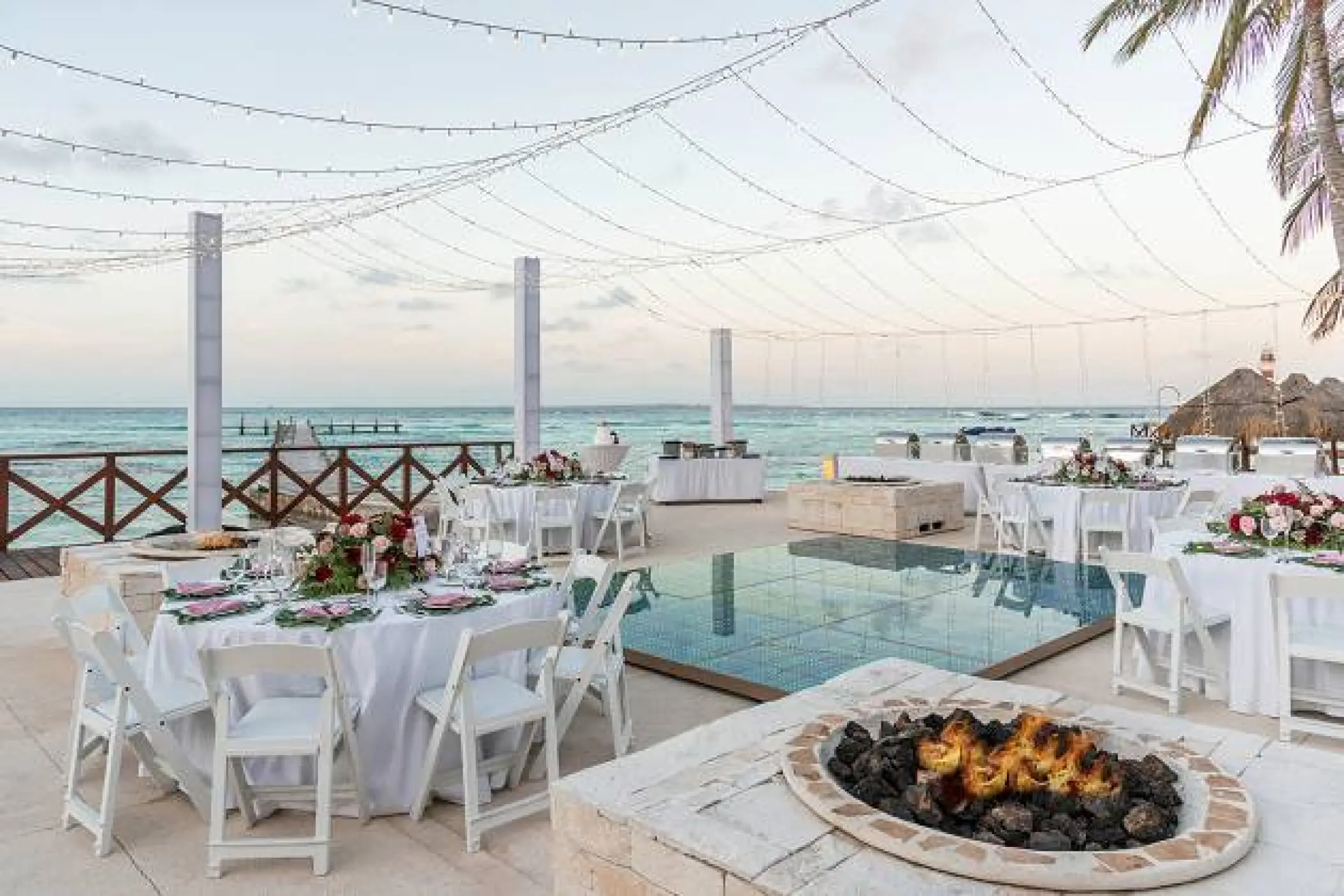 Outdoor wedding reception with a dance floor, fire pit, and string lights at Hyatt Ziva Cancun