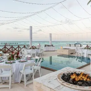 Outdoor wedding reception with a dance floor, fire pit, and string lights at Hyatt Ziva Cancun
