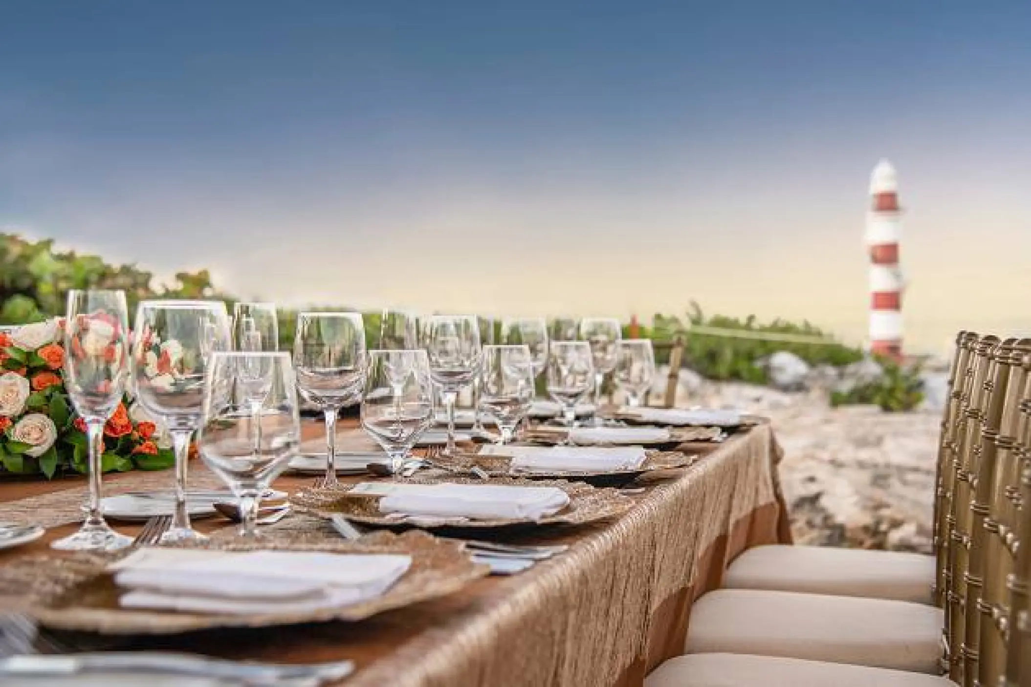 Wedding reception table with floral arrangements and glassware overlooking the lighthouse at Hyatt Ziva Cancun