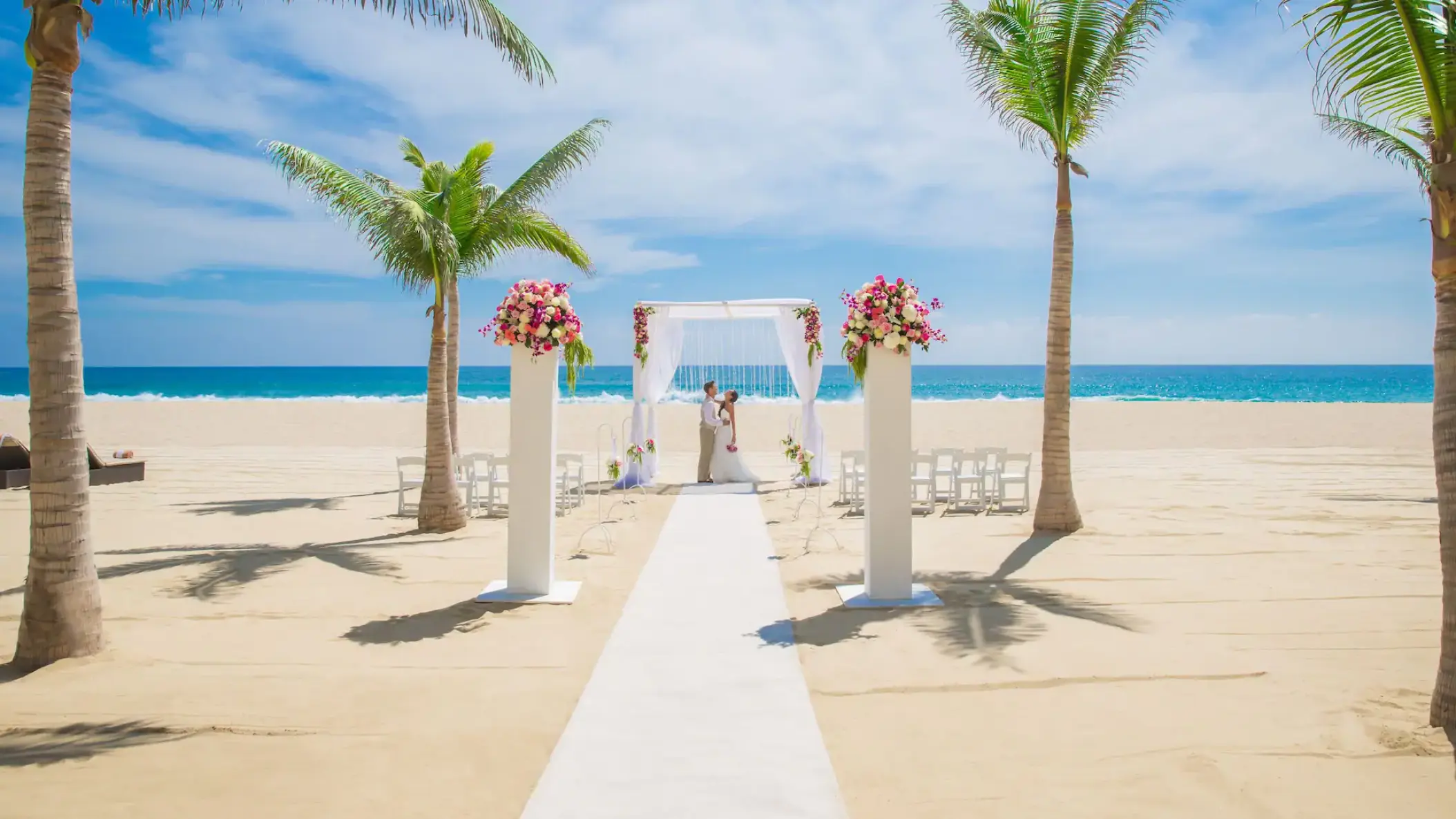 Beachfront wedding ceremony with white huppah and floral pillars at Hyatt Ziva Los Cabos, Cabo San Lucas