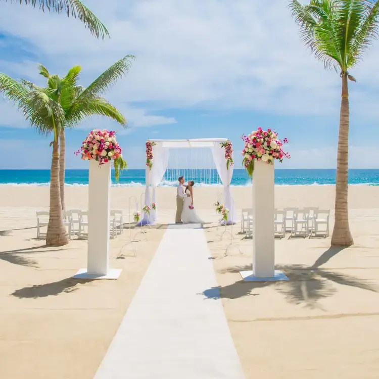 Beachfront wedding ceremony with white huppah and floral pillars at Hyatt Ziva Los Cabos, Cabo San Lucas