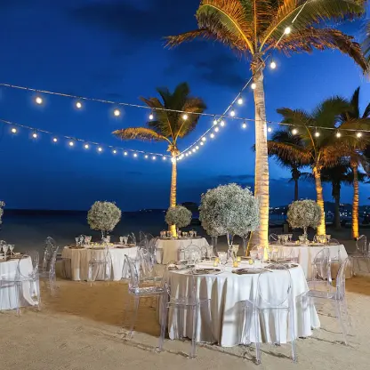 Beachfront wedding reception with string lights and white floral centerpieces at Hyatt Ziva Los Cabos, Cabo San Lucas
