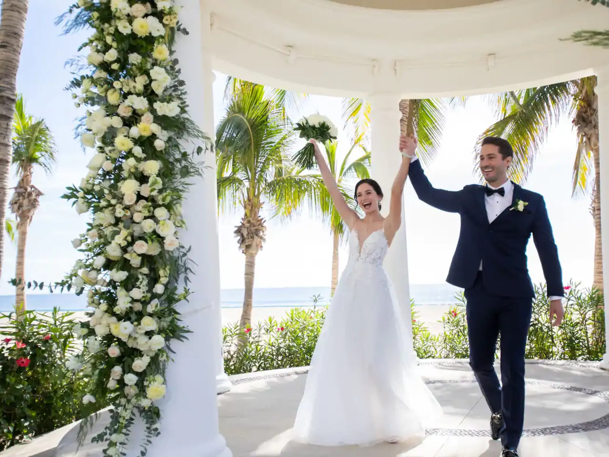 Bride and groom celebrating inside a floral white gazebo at Hyatt Ziva Los Cabos, Cabo San Lucas