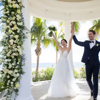Bride and groom celebrating inside a floral white gazebo at Hyatt Ziva Los Cabos, Cabo San Lucas