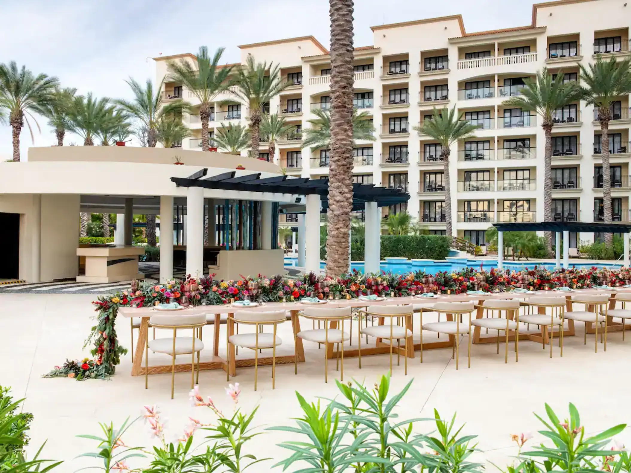 Long wooden wedding reception table with floral garland by the pool at Hyatt Ziva Los Cabos, Cabo San Lucas