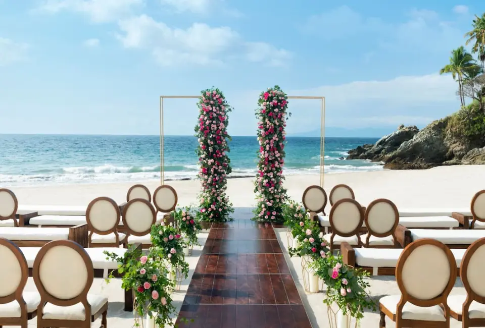 Beachfront wedding ceremony setup with floral pillars at Hyatt Ziva Puerto Vallarta