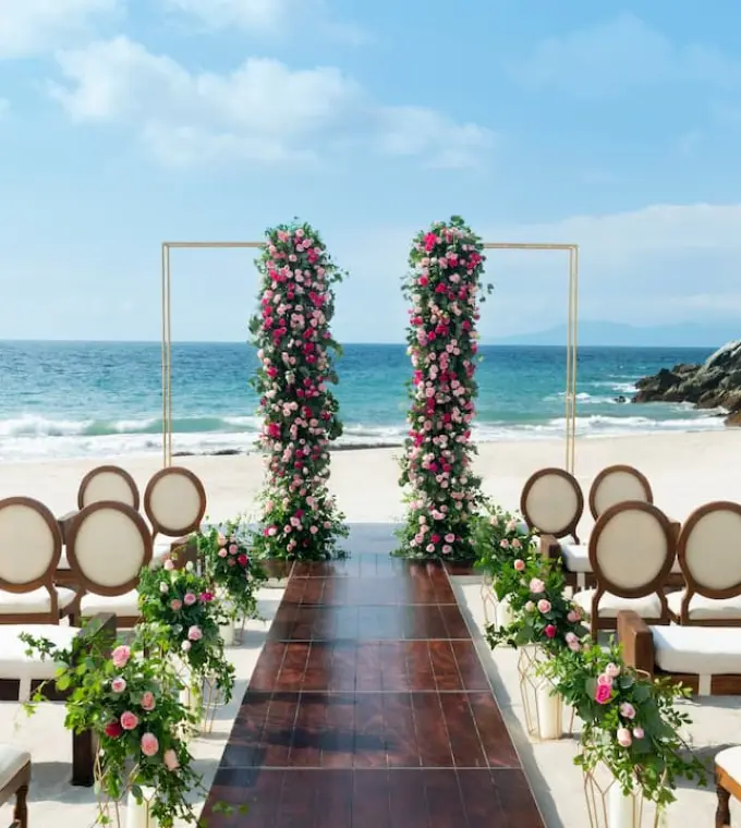 Beachfront wedding ceremony setup with floral pillars at Hyatt Ziva Puerto Vallarta