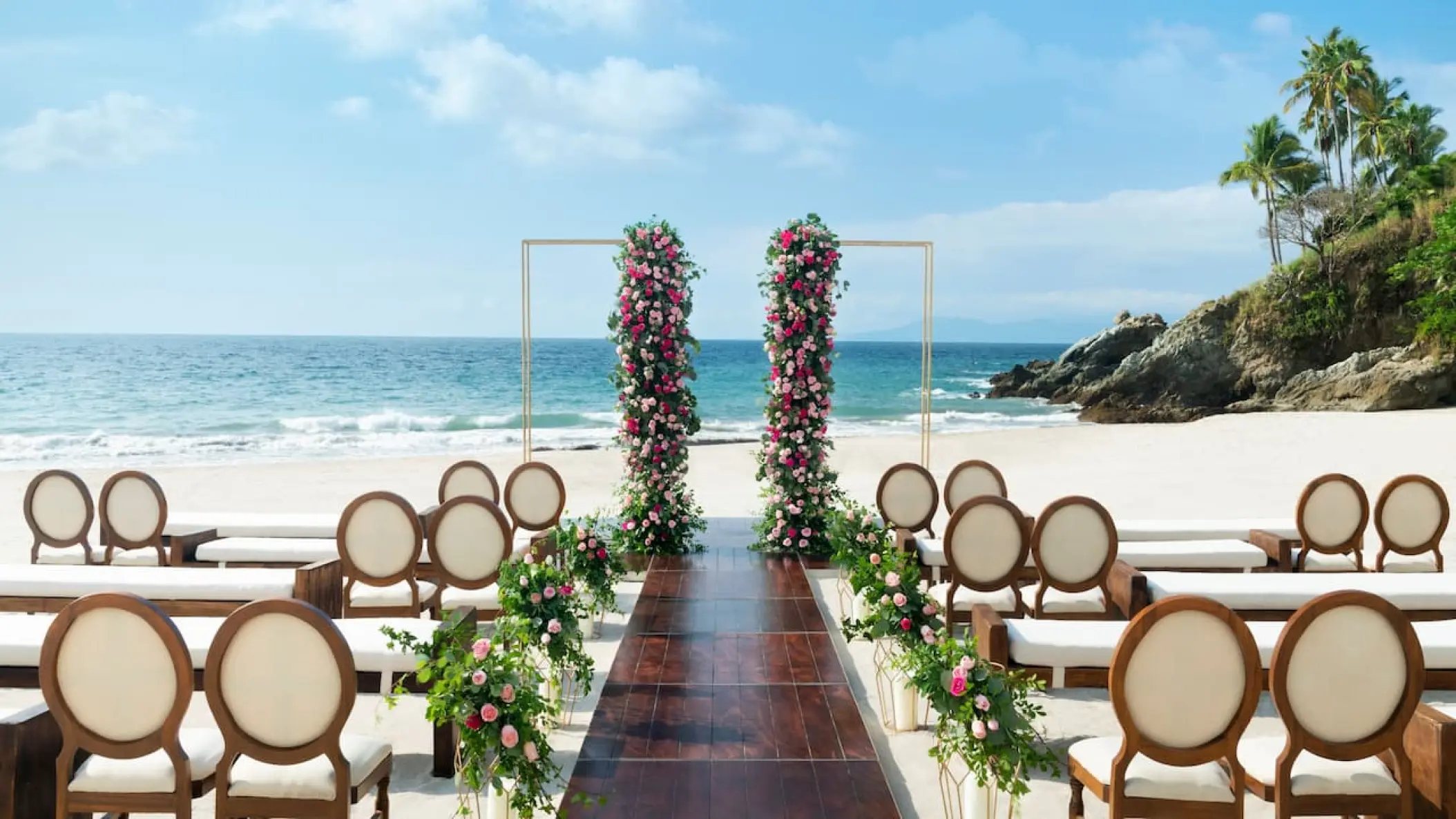 Beachfront wedding ceremony setup with floral pillars at Hyatt Ziva Puerto Vallarta