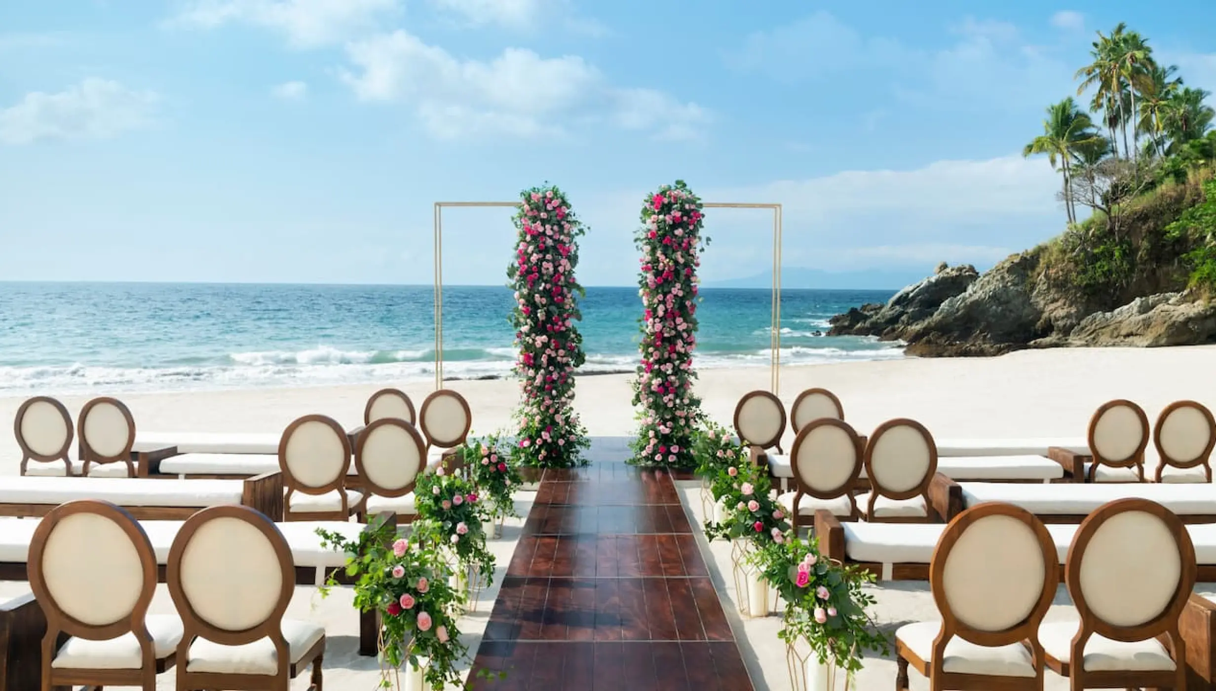 Beachfront wedding ceremony setup with floral pillars at Hyatt Ziva Puerto Vallarta