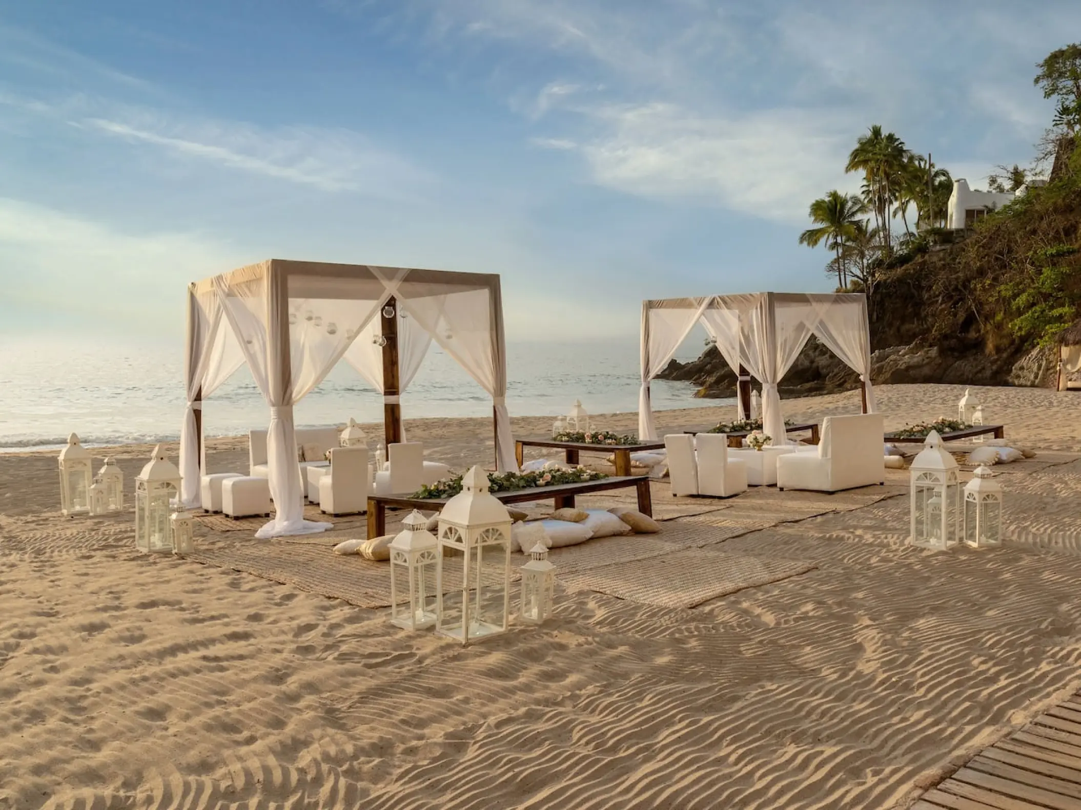 Beachfront wedding reception setup with white cabanas and lanterns at Hyatt Ziva Puerto Vallarta