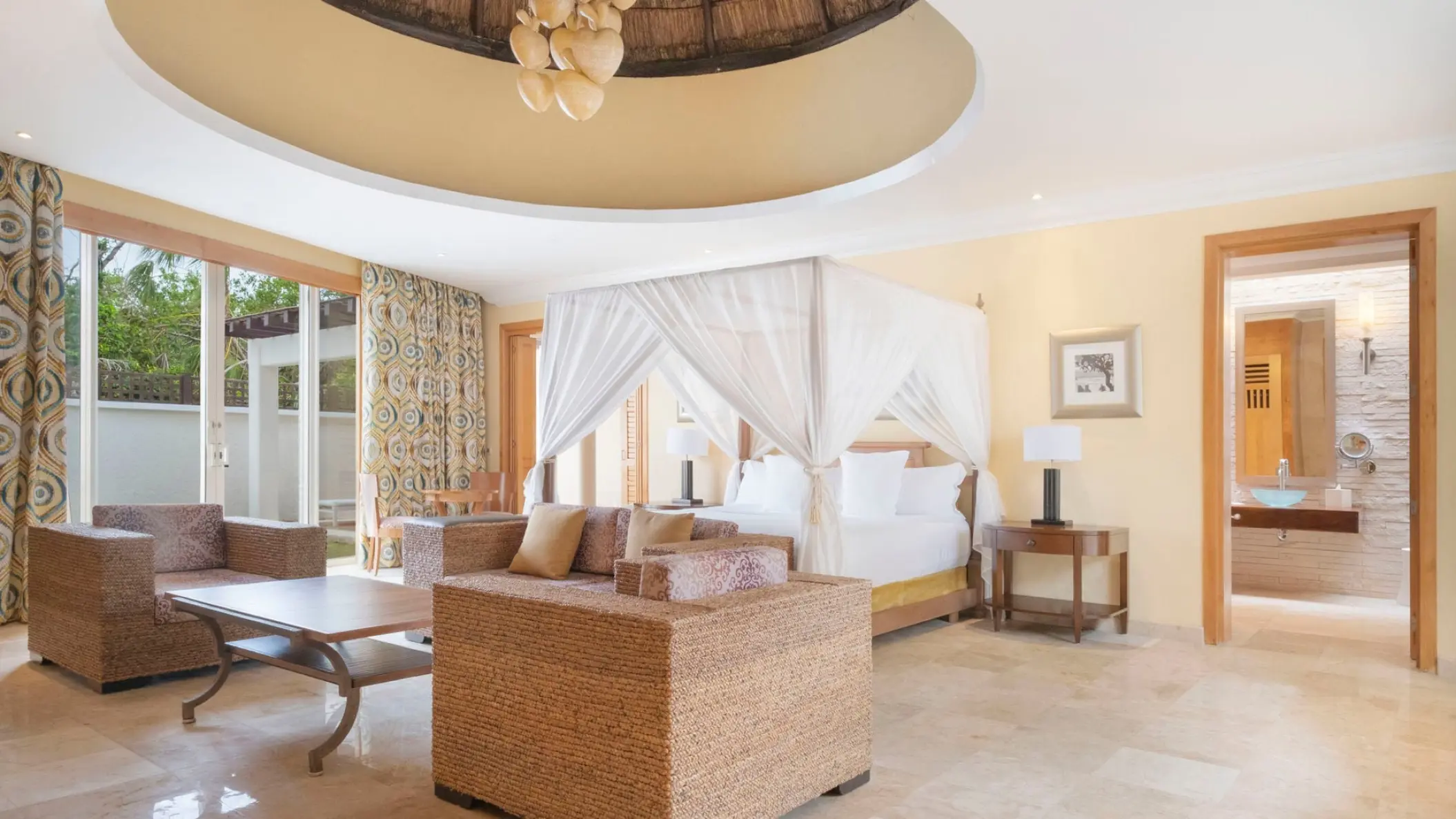 Canopy bed and lounge area in a suite at JOIA Paraiso, Riviera Maya