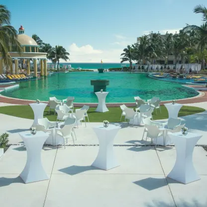 Cocktail hour setup with white high-top tables by the JOIA Paraiso pool, Riviera Maya